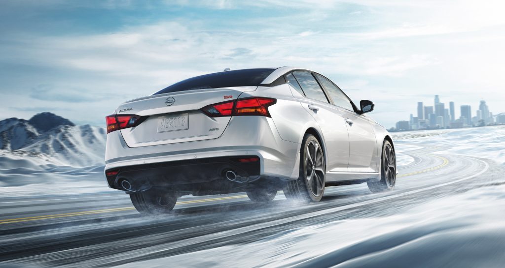 Picture of a white Nissan Altima driving down a snowy road.